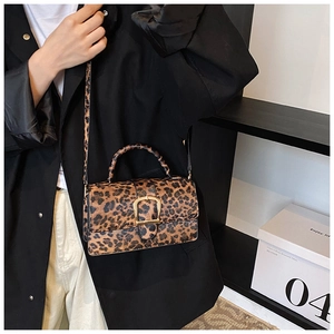 Detail of vintage leopard print crossbody bag with gold buckle and slim leather strap