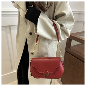 Détail du sac rouge vintage avec rabat ondulé et fermoir métallique doré brillant