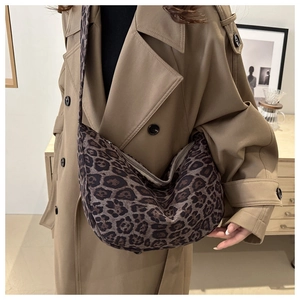 Detailed view of large leopard print tote bag with wide strap on a khaki trench coat