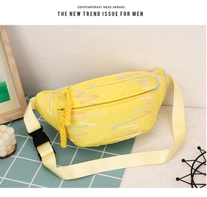 Close-up of yellow corduroy crossbody bag featuring colorful wave embroidery and adjustable strap
