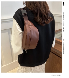 Detail of brown leather waist bag with adjustable strap and metal zipper on back view