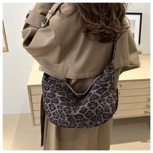 Detail view of large leopard print crescent bag on model showing rustic fashion style