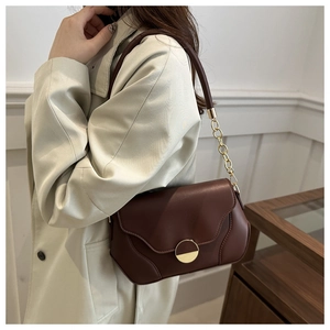 Détail d'un sac à bandoulière en cuir marron avec chaîne dorée et boucle métallique