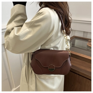 Détail d'un sac bandoulière marron caramel avec chaîne dorée et fermoir rond rétro