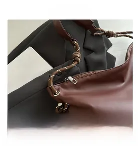 Detail of brown PU leather bag with rope strap, knot design, and silver zipper on magazine