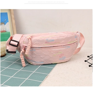 Detail of pink corduroy moon bag featuring colorful wave embroidery and woven zipper pull