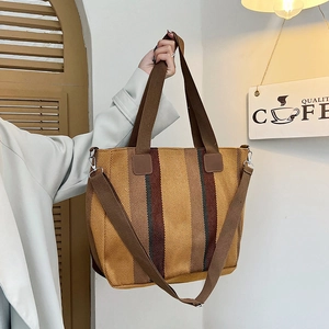 Close-up of a striped woven tote bag with brown handles and adjustable shoulder strap