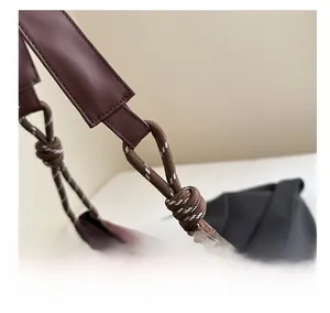 Detail of reddish-brown leather tote featuring unique thick knotted rope strap attachment