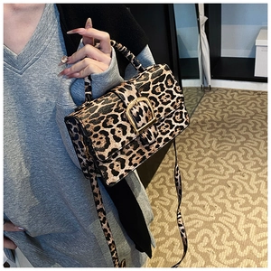 Detailed shot of leopard print shoulder bag with gold hardware worn by model
