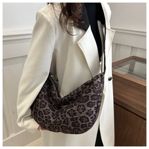 Detailed view of leopard print crossbody bag worn by a model in a modern interior setting