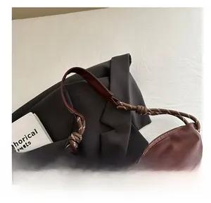Detail of brown tote bag featuring rope shoulder straps and durable metal zipper closure