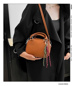 Close-up of brown PU leather bowling bag with colorful braided cord charms and shoulder strap