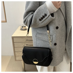 Sac bandoulière noir avec fermoir demi-cercle doré et détail élégant de bandoulière chaîne