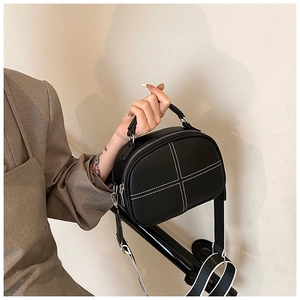 Detail of black pebbled leather handbag with white contrast stitching and wide strap