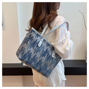 Detail of blue denim tote bag with silver sequins and beige leather straps