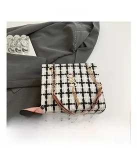 Detail of black and white tweed checkered bag with gold S hardware and tassel charm