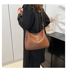 Detailed view of brown textured leather tote bag with stylish pleats and metallic buckle