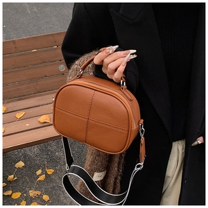 Brown lychee leather crossbody bag featuring wide striped strap and cross stitching detail