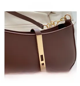 Detailopname van donkerbruine lederen tas met gouden gesp en luxe stikselwerk