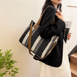 Striped canvas tote bag with brown handles and shoulder strap shown in a lifestyle scene