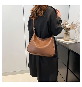 Adjustable strap detail on a vintage brown leather hobo bag worn by a model in a studio