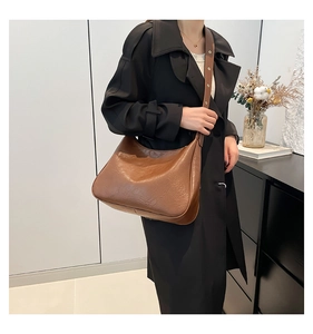 Close-up of brown PU leather shoulder bag with adjustable strap and golden buckle