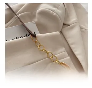 Detail van donkerbruine leren riem met gouden metalen ringen en fijn stiksel op schoudertas