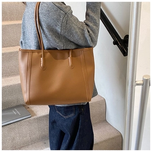 Detail of caramel leather tote bag with elegant long straps and fine stitching