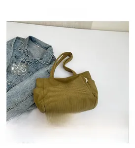 Detail of mustard yellow corduroy tote bag showing textured fabric and side pocket
