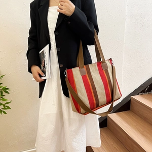 Detail of colorful striped canvas tote bag showing handle attachments and metal hooks