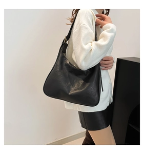 Close-up of black retro textured leather tote with elegant golden metal adjustment buckle