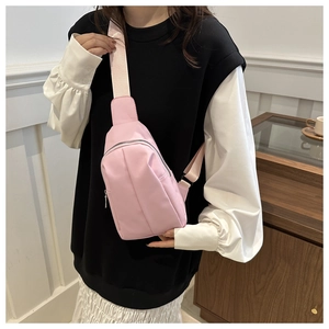 Detail view of pink nylon crossbody chest bag with adjustable strap and metal zipper