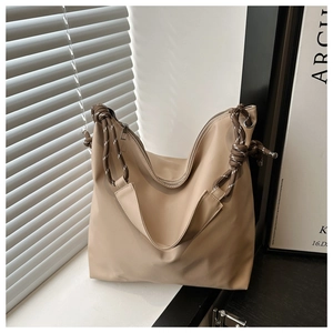 Detail of khaki tote bag featuring distinctive brown braided rope handles and silver zipper