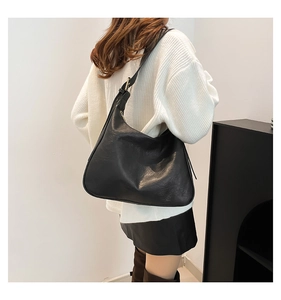Detail of black PU leather shoulder bag with lychee texture and gold metal buckle