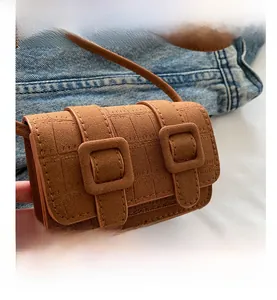 Detailed macro view of the brown faux suede mini bag with dual buckle design on denim