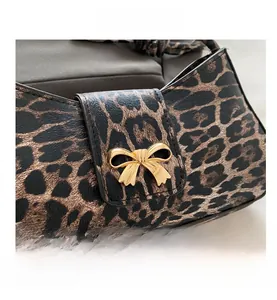 Detail of leopard print texture and gold bow metal buckle on a stylish shoulder bag