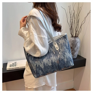 Detail of blue denim tote bag with silver sequins and metallic shoulder straps