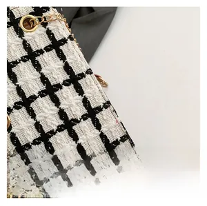 Close-up of black and white tweed texture on tote bag with premium gold chain link details