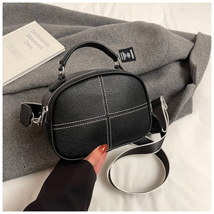 Close-up of black lychee grain leather pillow bag with white cross stitching detail
