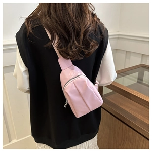 Rear view of a model wearing a light pink nylon crossbody chest bag with adjustable strap
