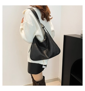 Detailed view of black large Hobo shoulder bag with golden buckle on wide strap