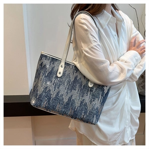 Detail of dark blue denim tote bag with silver sequins in geometric stripe pattern