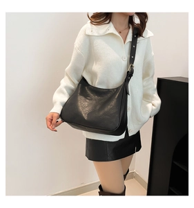 Detail shot of a black leather hobo bag with adjustable silver buckle on a shoulder strap