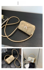 Détail d'un mini sac bandoulière doré métallisé avec un ornement papillon blanc
