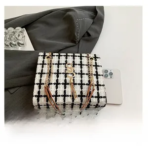 Detail view of black and white plaid tweed tote bag with gold S hardware and chain strap