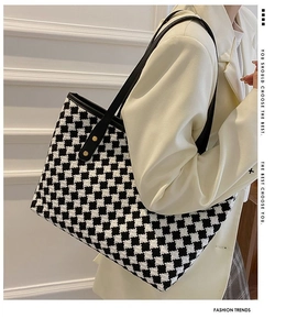 Detail of houndstooth tote bag featuring textured fabric and decorative gold rivets