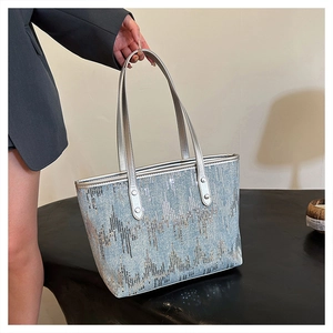 Detail of blue sequin tote bag with silver leather handles and metallic rivet reinforcement