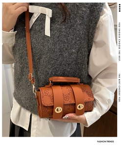 Brown Boston bag with cherry blossom print and gold metal twist lock on grey sweater
