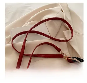 Detail of red oil-wax leather shoulder bag with adjustable strap and bear plush charm