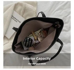 Detailed interior of a spacious black leather tote bag showing makeup and accessories